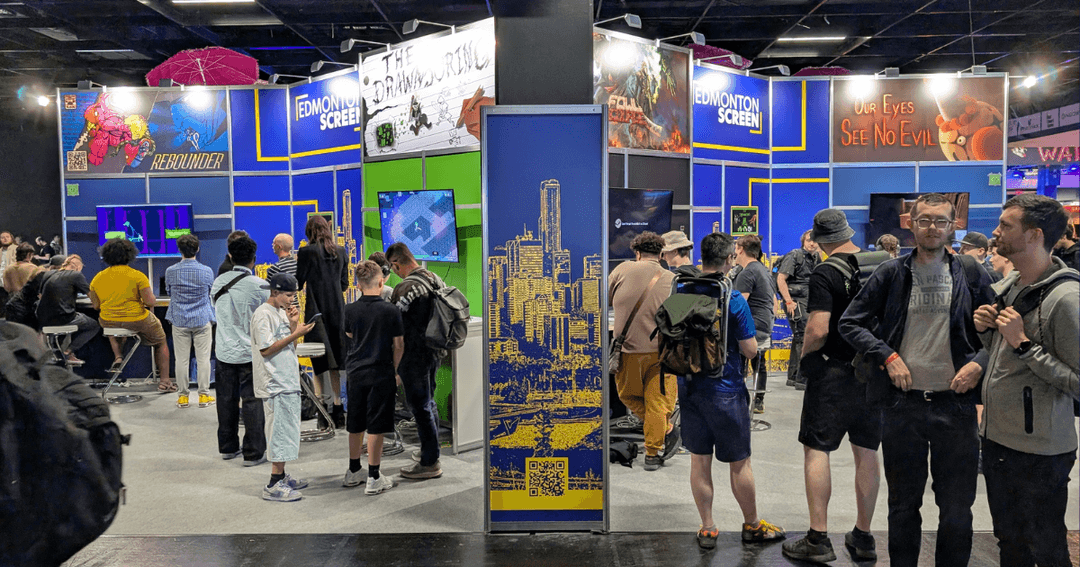 Attendees playing video games from Edmonton indie studios at Edmonton Screen's gamescom 2025 booth.