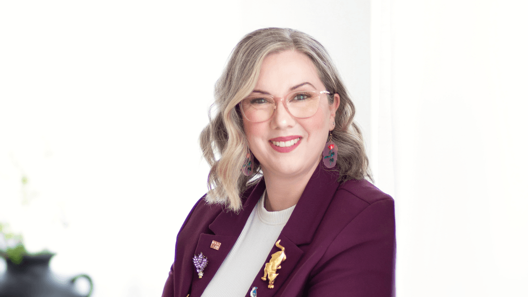 Sarah Taylor, Edmonton-based film editor and recipient of Edmonton Screen's Elevation Program, smiling with a maroon blazer.