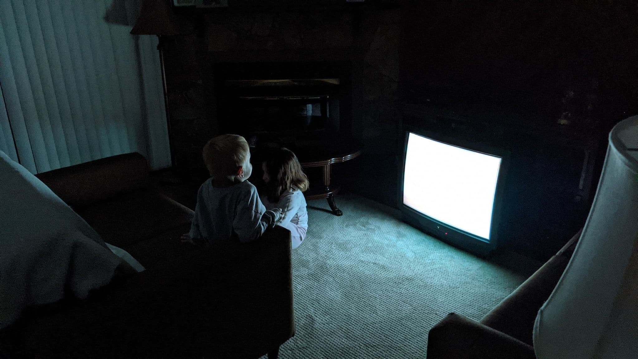 Two children, Kevin and his sister Kaylee, are seated in front of an older-style CRT television screen.