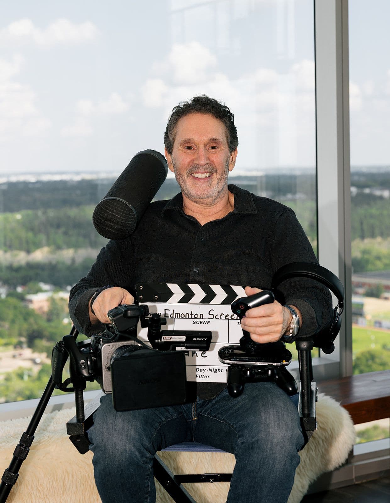 Luke Azevedo, Edmonton Screen’s CEO, smiling while seated with professional camera equipment and a clapperboard.