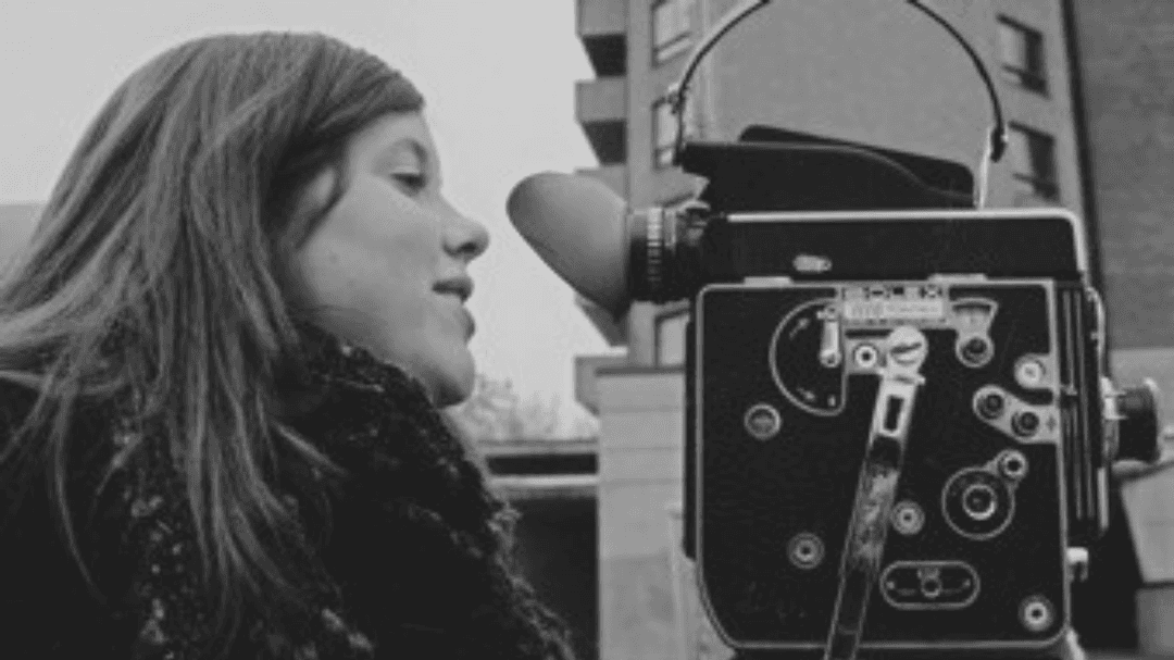 Katrina Beatty filming with a vintage camera in a black-and-white photo, capturing the craft of Edmonton filmmakers.
