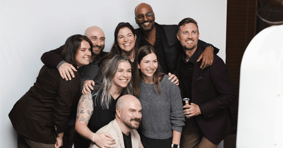 Nine people smiling together at a photo booth in front of a white backdrop at Edmonton International Film Festival's Closing Party..